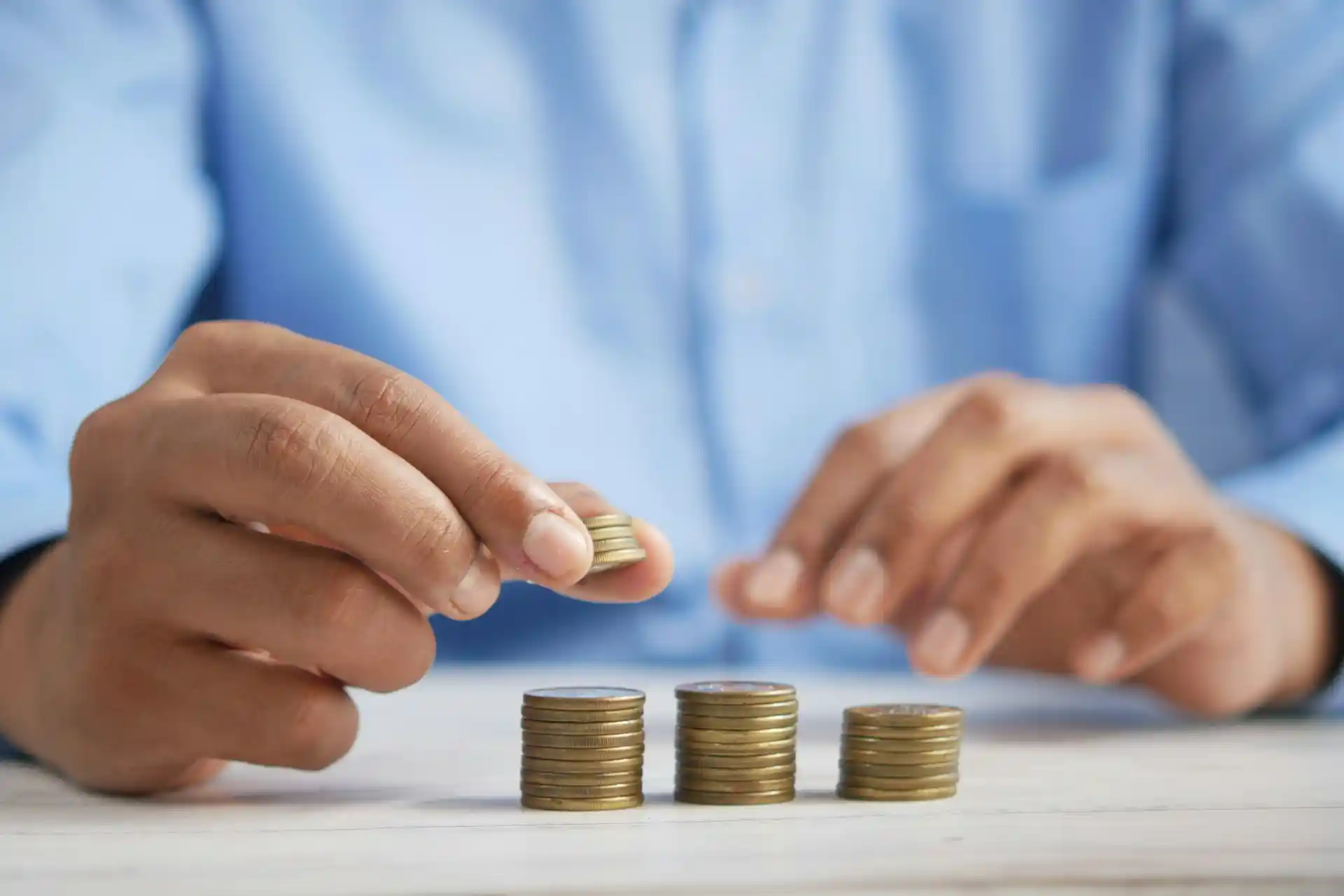 Hands stacking coins into piles, symbolizing the careful and strategic approach needed to invest in emerging markets safely.
