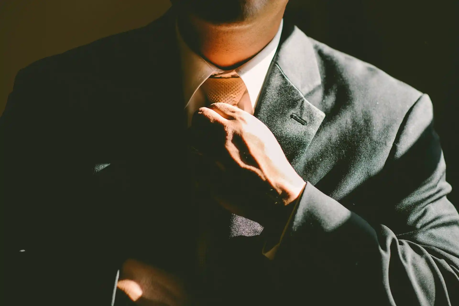 A man in a suit adjusting his tie, symbolizing the focus and precision, key qualities of visionary leadership in business.